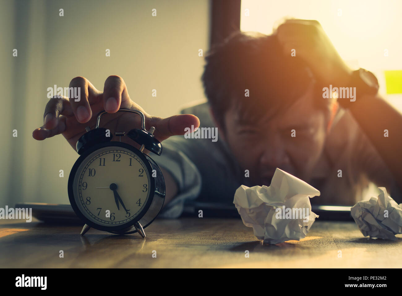 overtime and tired working businesman reaching out to stop alarm clock