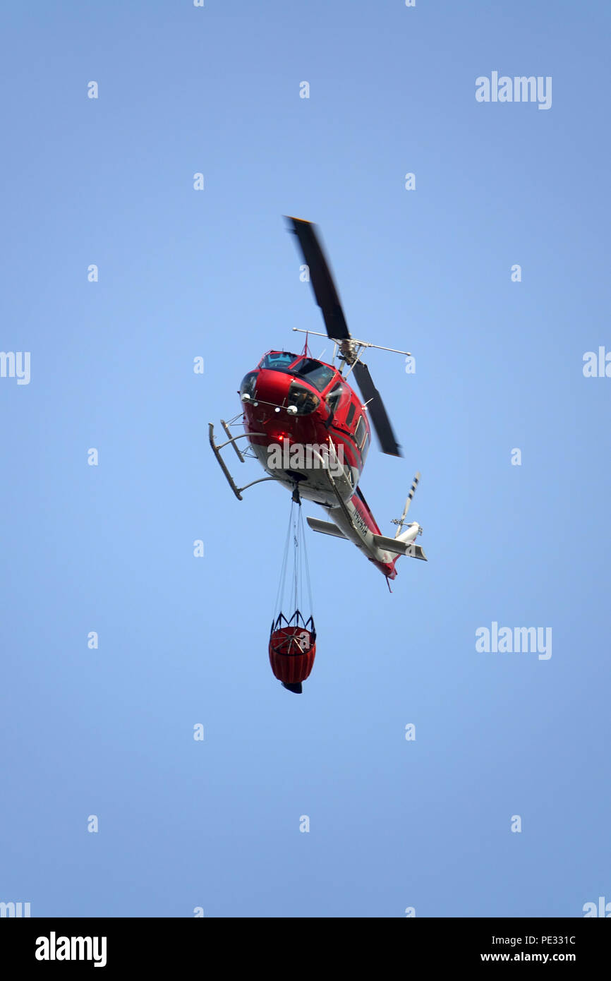 A helicopter carries a water bucket to help fight wildfires. Helicopters are a primary aerial support system to fight wildfires by dropping water on a Stock Photo