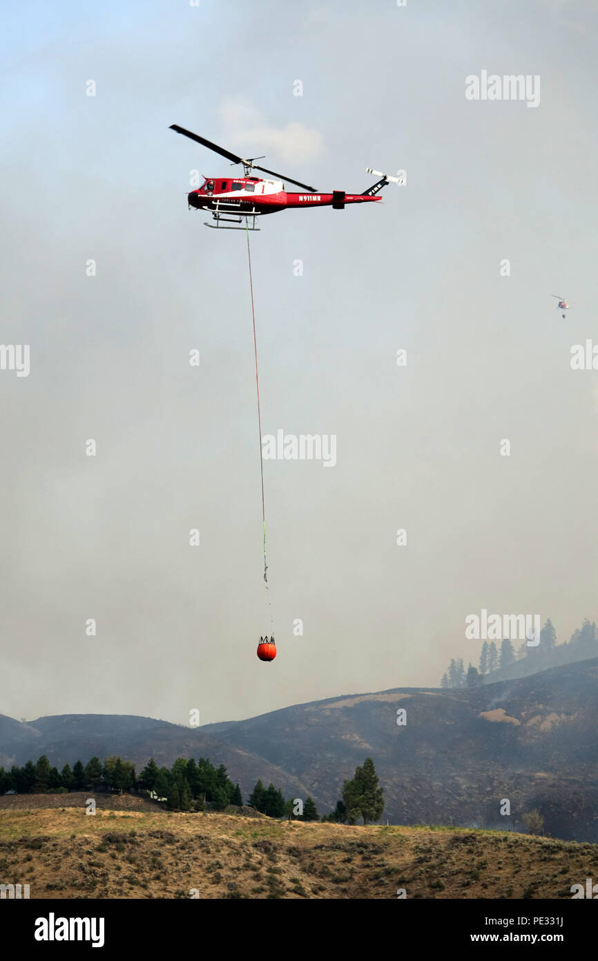 Helicopters are a primary aerial support system to fight wildfires by dropping water on active firelines to help firefighters gain control. Stock Photo