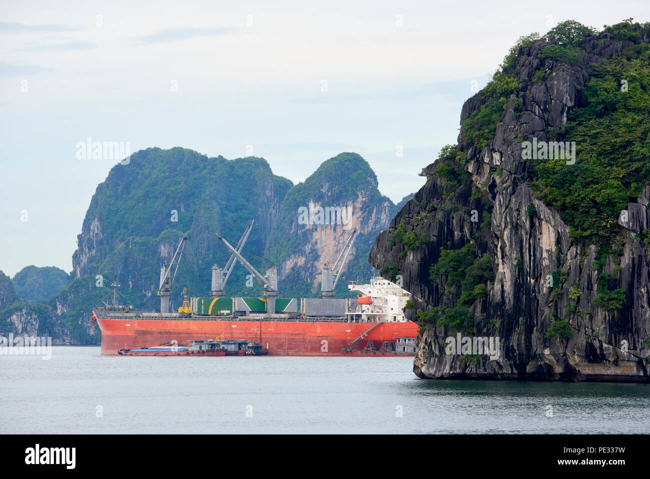 Mountain Halong Bay, North Vietnam, with industrial transport ship in the background. The islet resembles a human face in profile when seen from the s Stock Photo