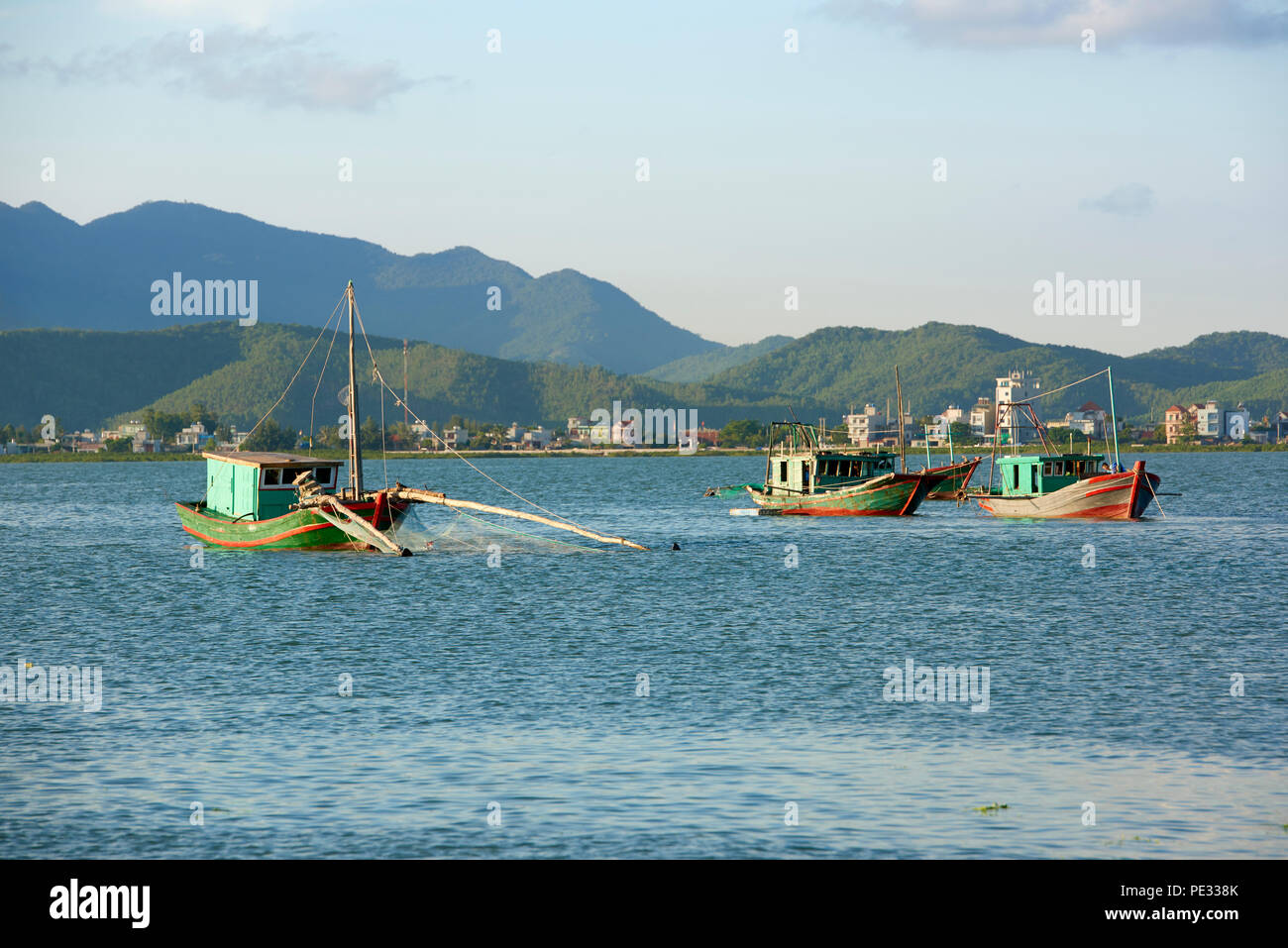 Three small fishing boats being lit by warm sunlight in Bai Tu Long Bay, North Vietnam. Stock Photo