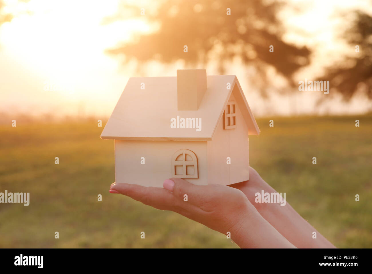 Image of woman holding small wooden house outdoors at sunset light ...