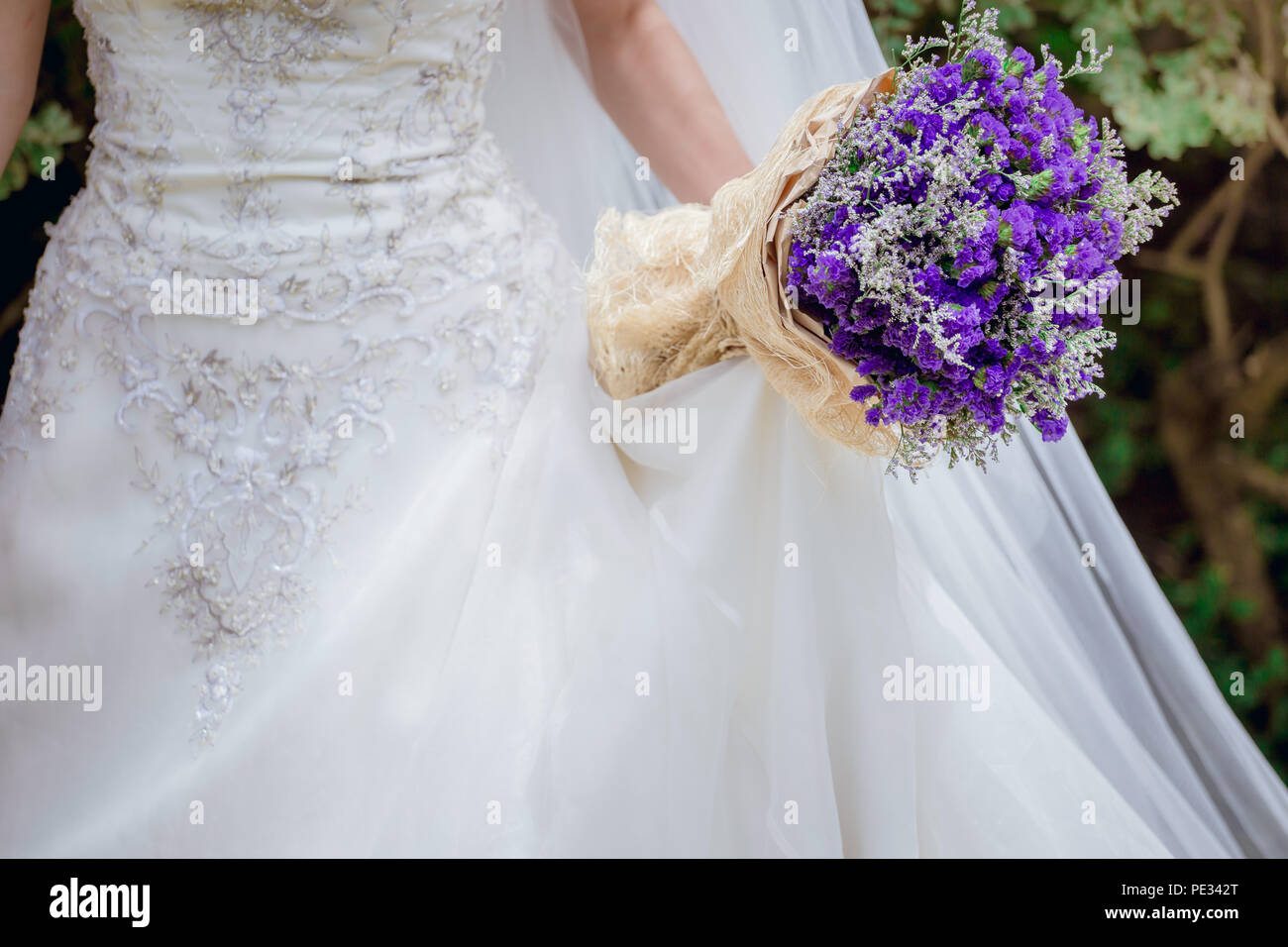 Newlyweds with a bouquet of beautiful flowers is the symbol of love and marriage. Stock Photo