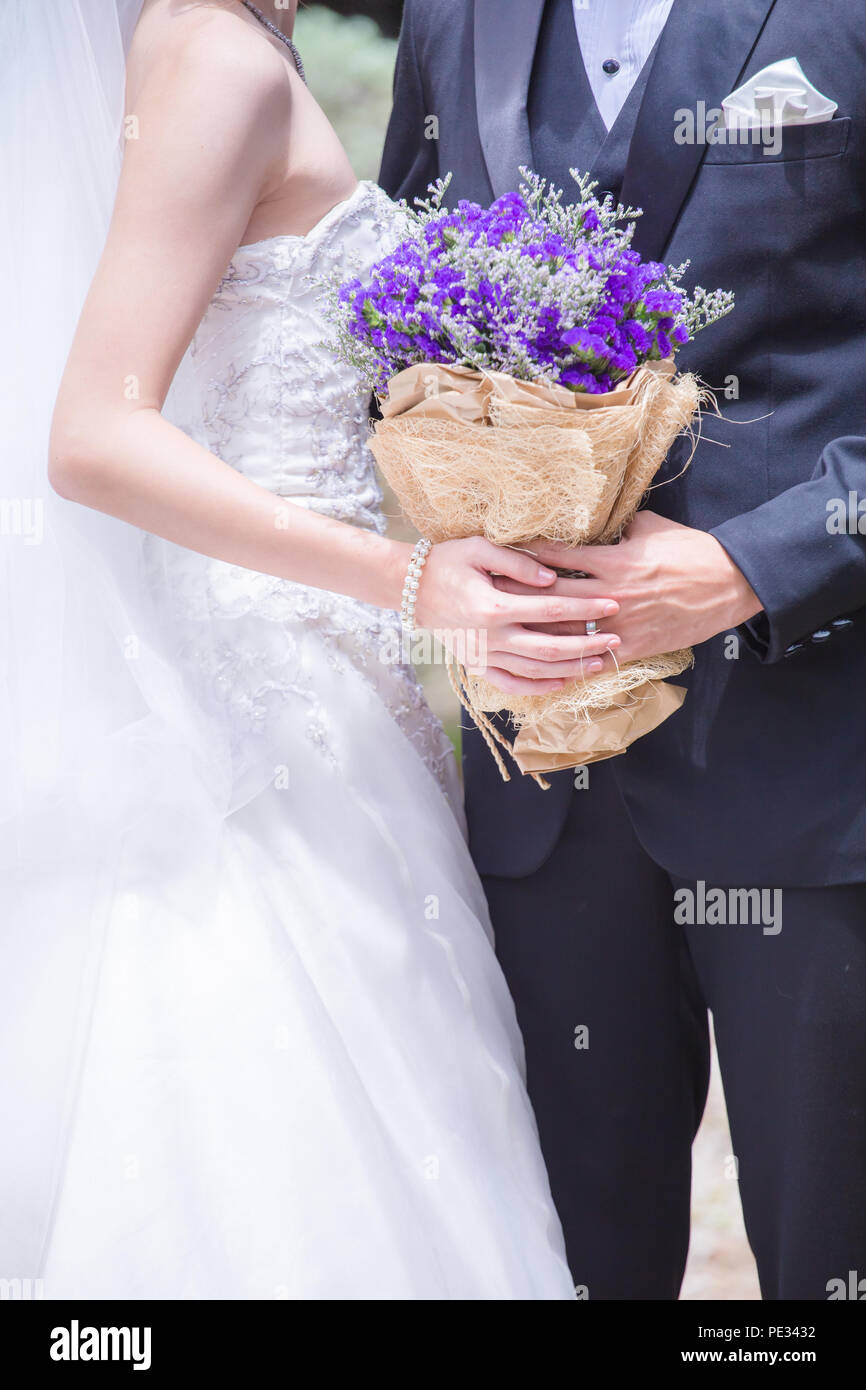 Newlyweds with a bouquet of beautiful flowers is the symbol of love and marriage. Stock Photo