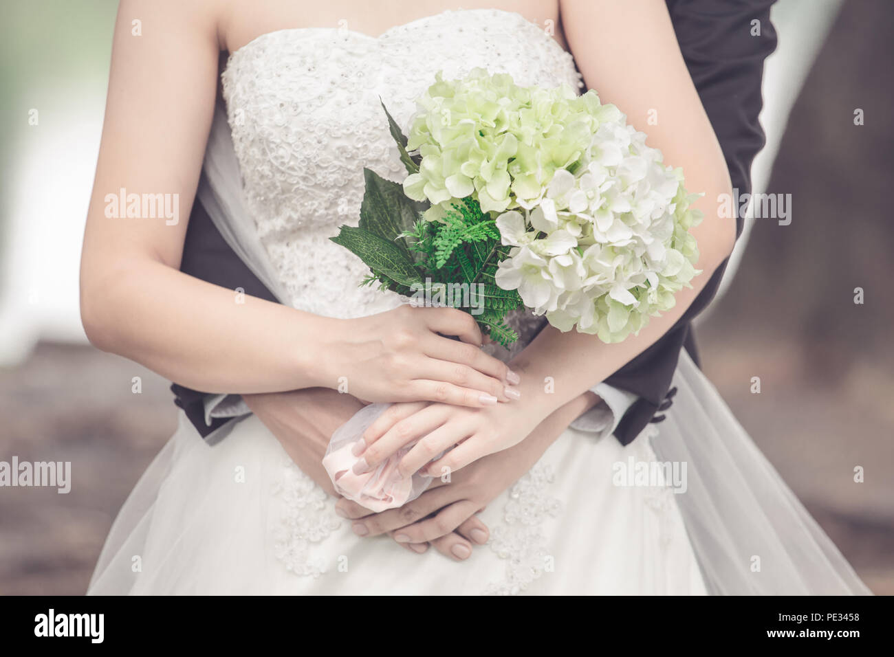 Married bride and groom embracing each other with a bouquet of flowers as a symbol of love and happiness. Stock Photo
