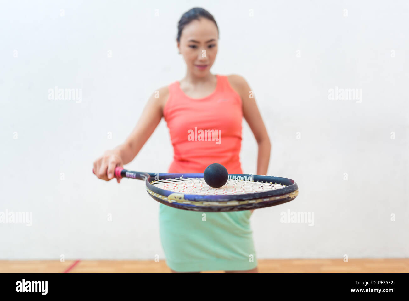 Close-up of a rubber hollow ball on the new squash racket of a fit woman Stock Photo