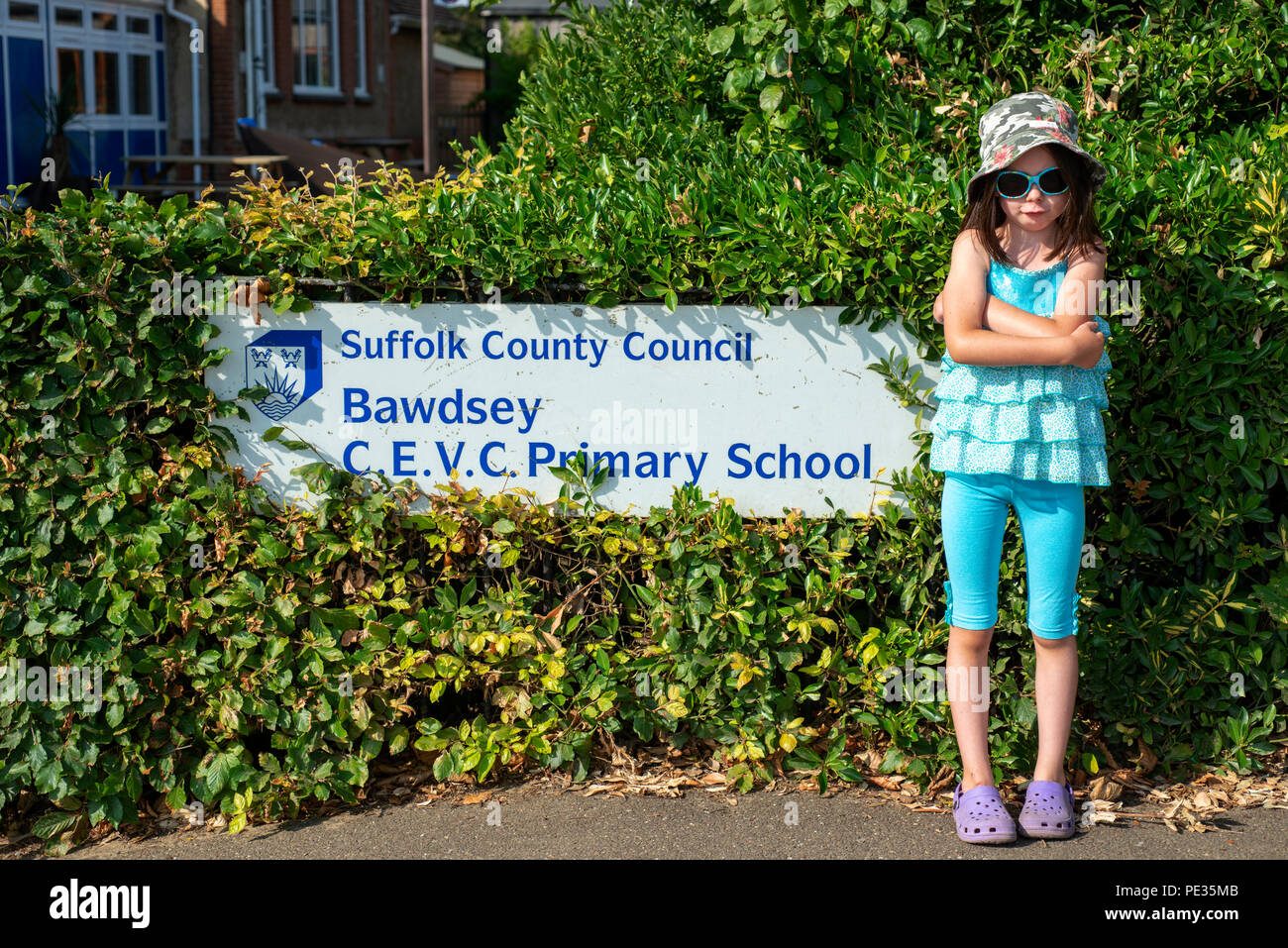 Young girl standing outside her school during the long summer holidays Stock Photo
