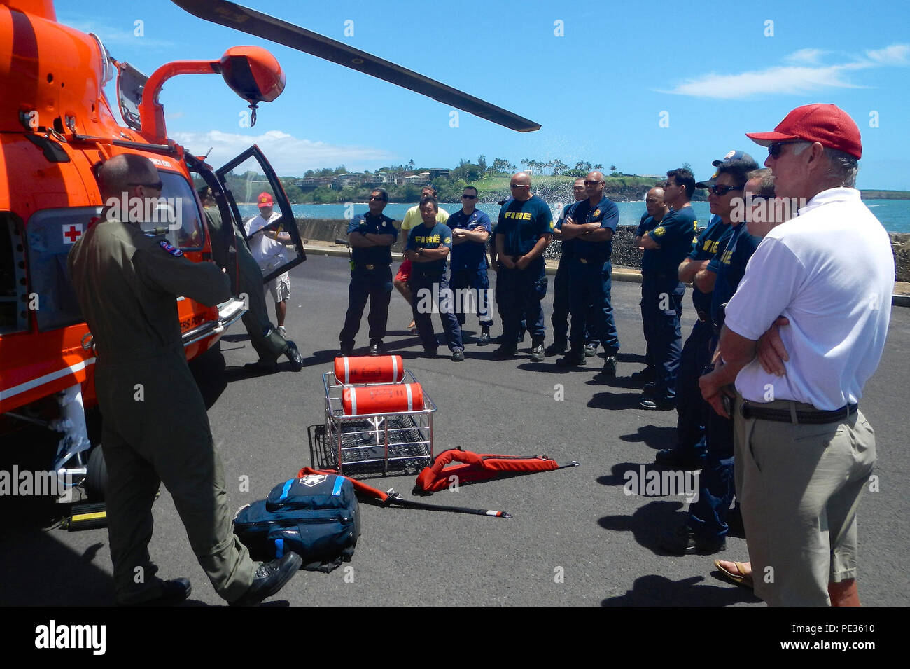 Lt. Samuel Pemberton, an MH-65 Dolphin helicopter pilot from Coast Guard Air Station Barbers Point, provides training to search and rescue exercise participants on the equipment and procedures used by the Dolphin crew in SAR cases during a search and rescue exercise in Kauai, Hawaii, Sept. 3, 2015. The exercise brought together the Coast Guard, Kauai Fire Department and Ocean Safety. (U.S. Coast Guard photo by Coast Guard Sector Honolulu/Released) Stock Photo
