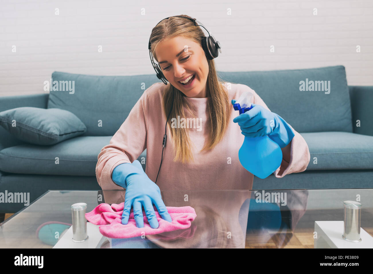 Happy woman with headphones listening music while cleaning house.Image