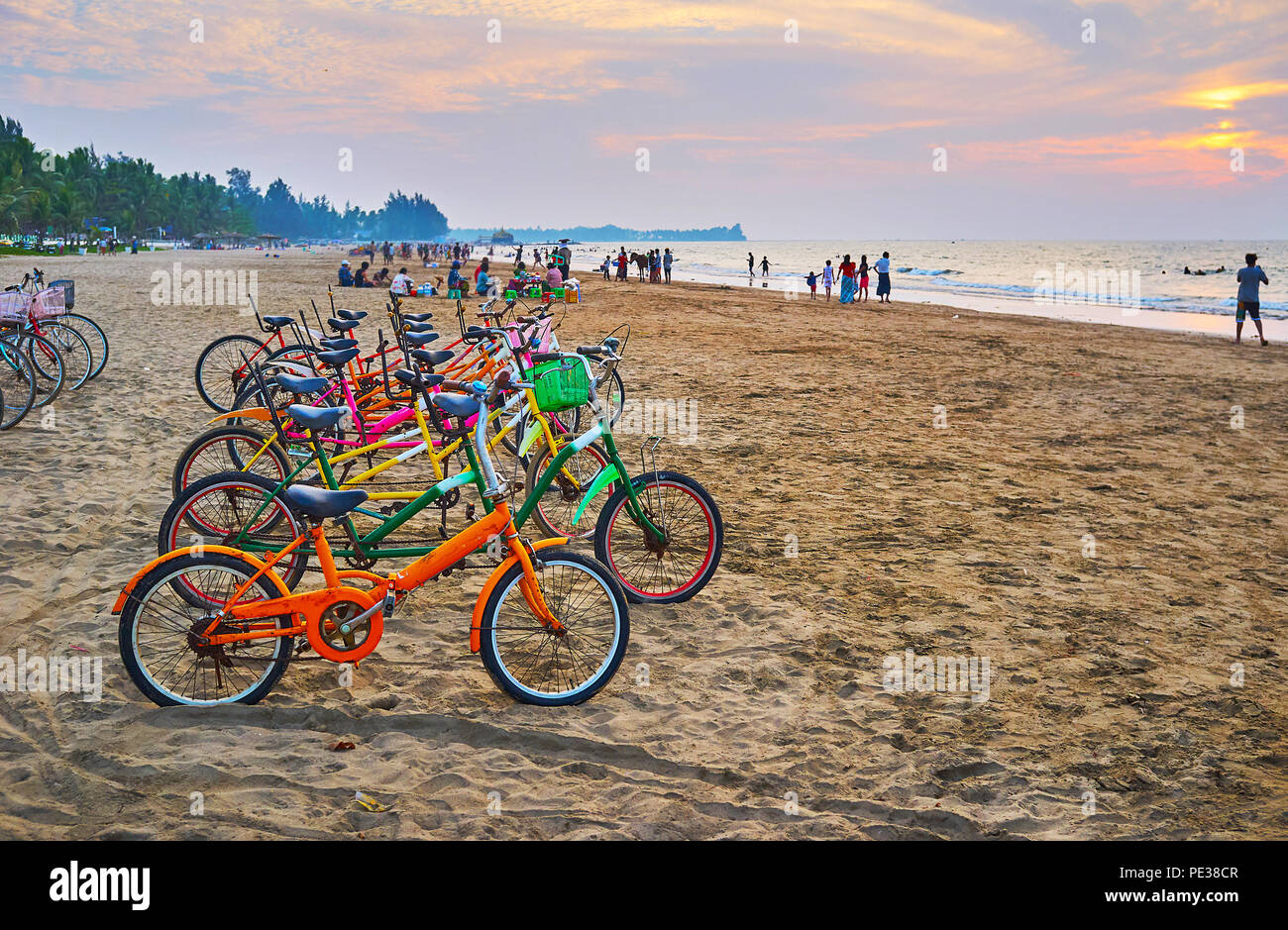 Bike ride along the beach is traditional Burmese time spending, people often rent the cycles on coast and ride till dark night, Chaung Tha, Myanmar. Stock Photo