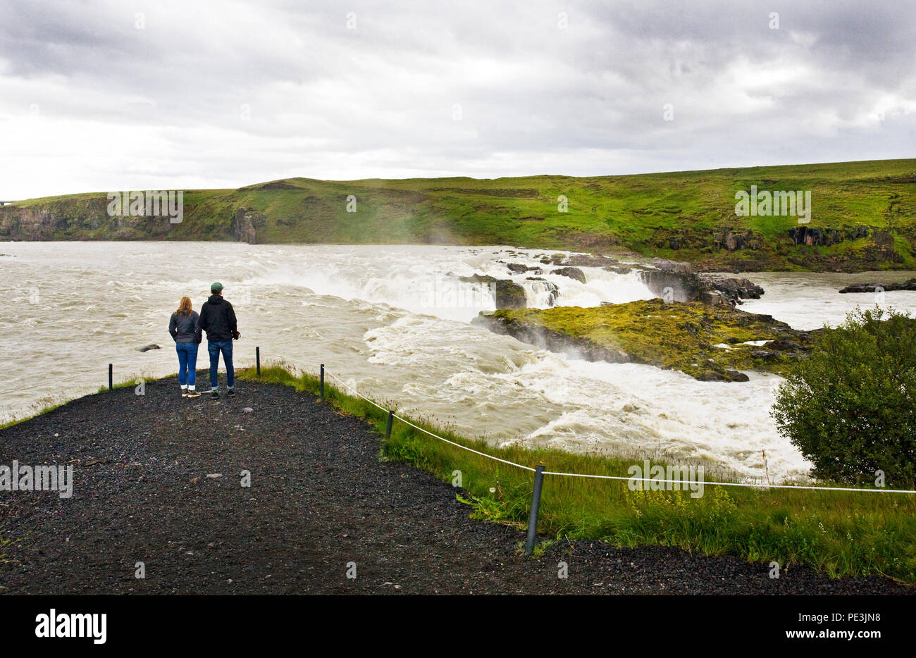 Visitors admire the power of  the Thjorsa River at Urrioafoss Waterfall in southern Iceland. The Thjorsa River is Iceland's longest river. Stock Photo