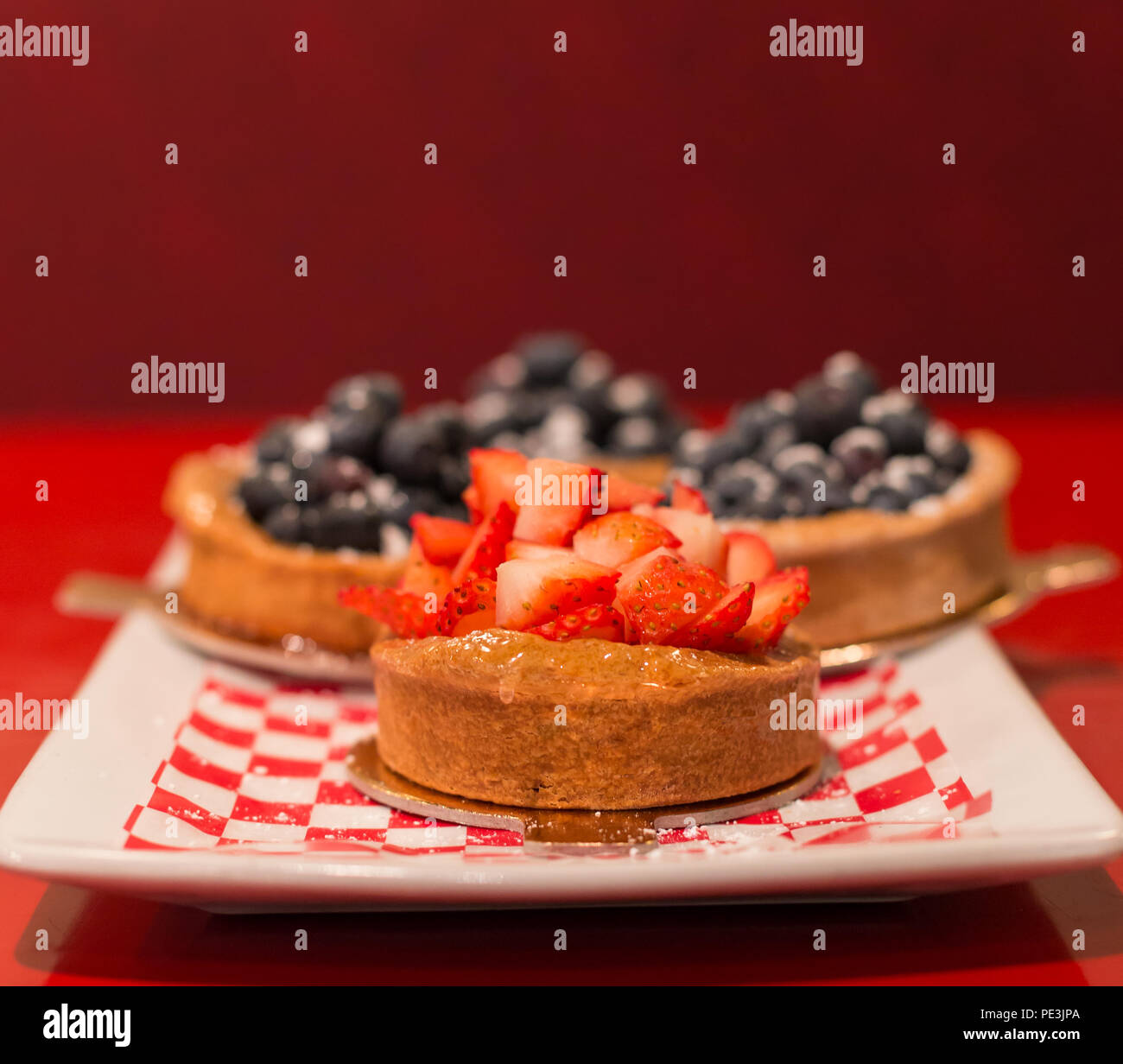 Strawberry tart with blueberry tarts in the background. Stock Photo