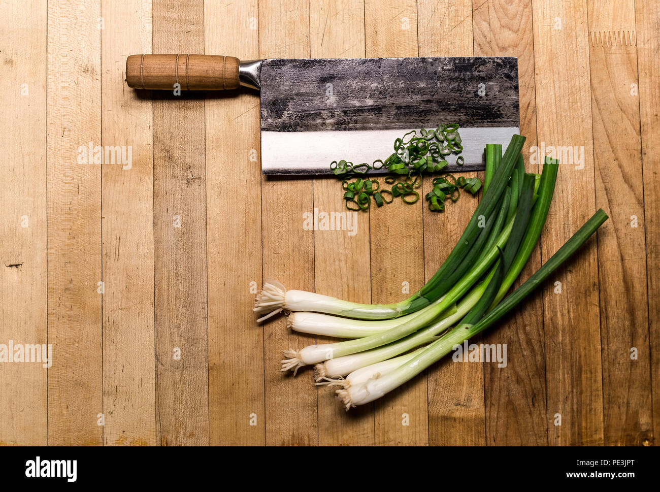 Chinese chopping knife with green onions on a wood cutting board Stock Photo Alamy