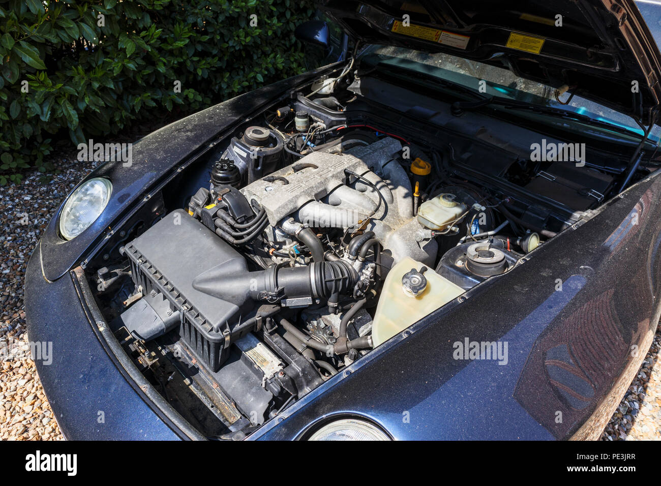 Open bonnet (hood) of a vintage Porsche 968 and the 3 litre straight-four engine (Front longitudinal inline four cylinder water cooled 16v VarioCam) Stock Photo