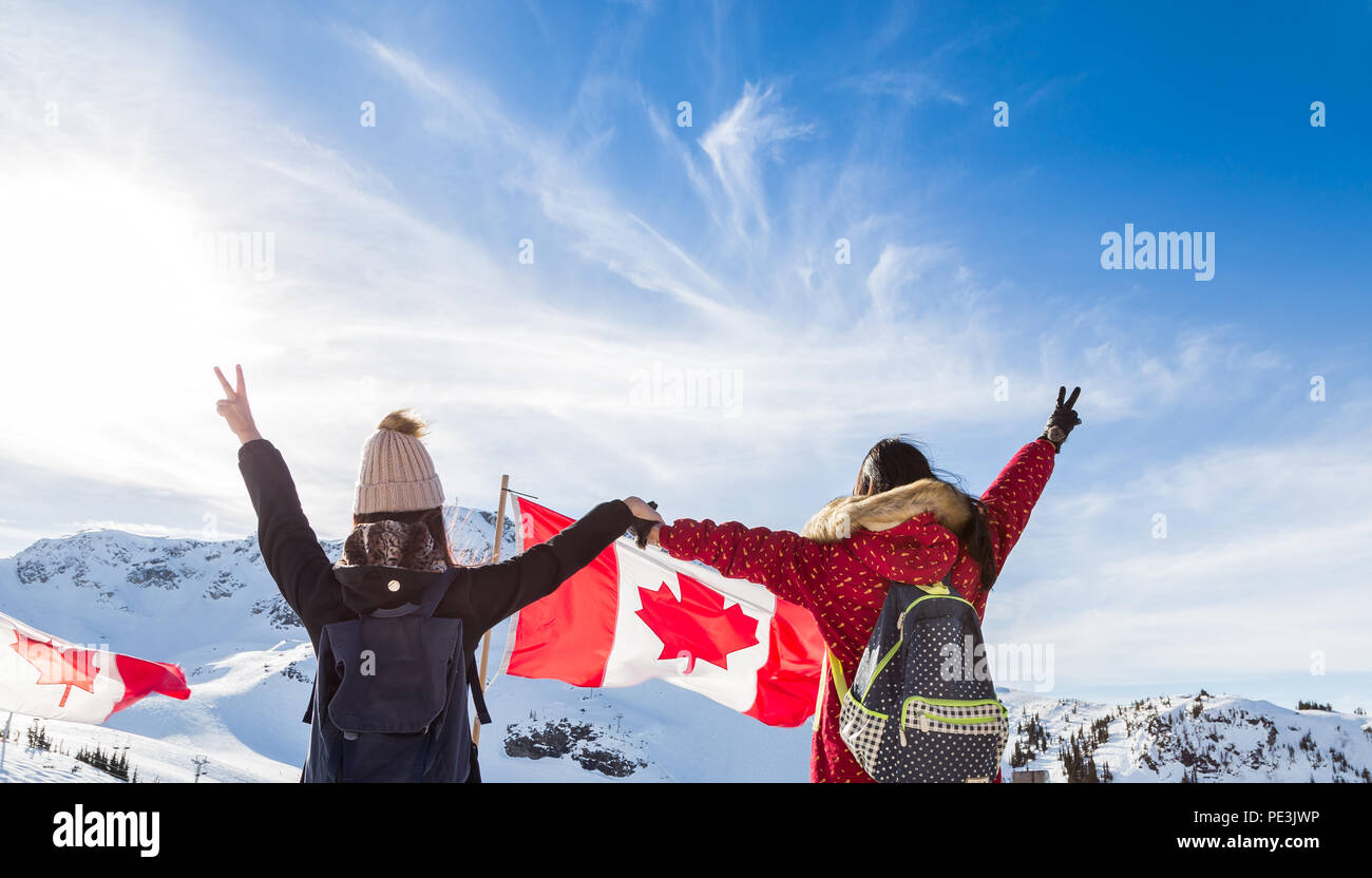 Two girls holding hands in front of a Canadian flag in Whistler. Stock Photo