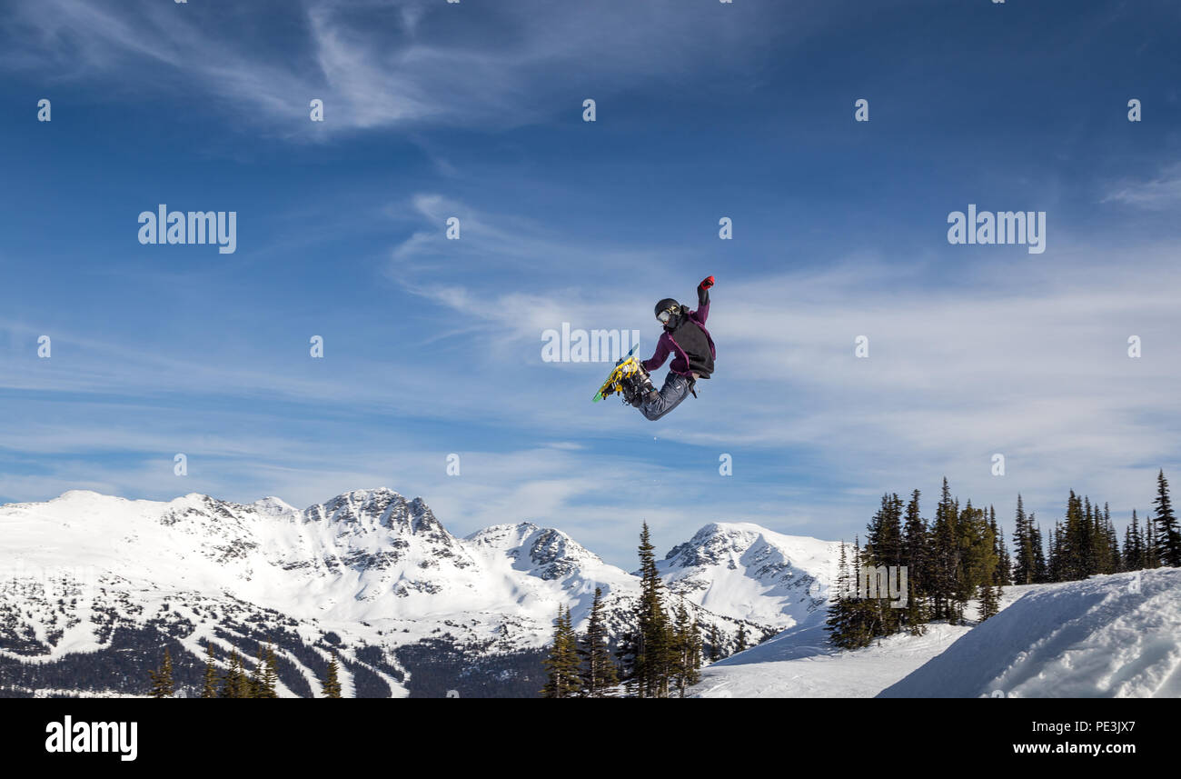 Snowboarder in mid-air grabbing the back of his board. Stock Photo