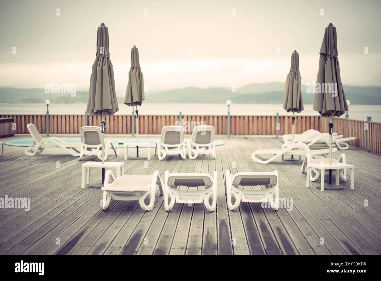Wooden deck beach sea ocean resort sun lounger umbrella hotel pool sky sunrise. Relax by the sea on the wooden terrace sunset evening Stock Photo