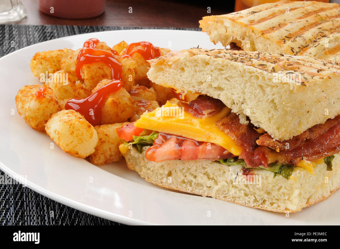 A bacon, lettuce and tomato panini with cheese and hash brown puffs