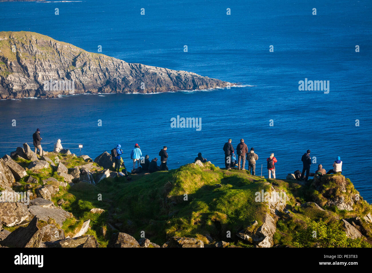 A group of birdwatchers are looking at the Atlantic Puffins and the beautiful scenery at the island Runde, Atlantic west coast, Norway. Stock Photo
