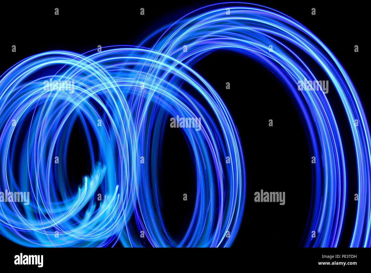 Blue light painting photography, long exposure, blue streaks of vibrant color against a black background Stock Photo