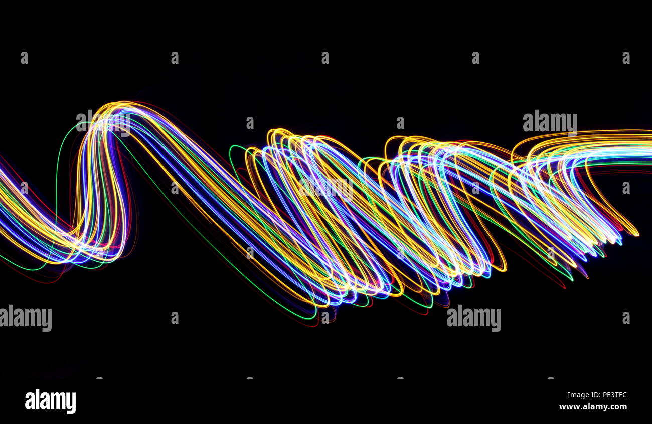 Multi color light painting photography, gold, red, green and blue waves of vibrant color against a black background Stock Photo