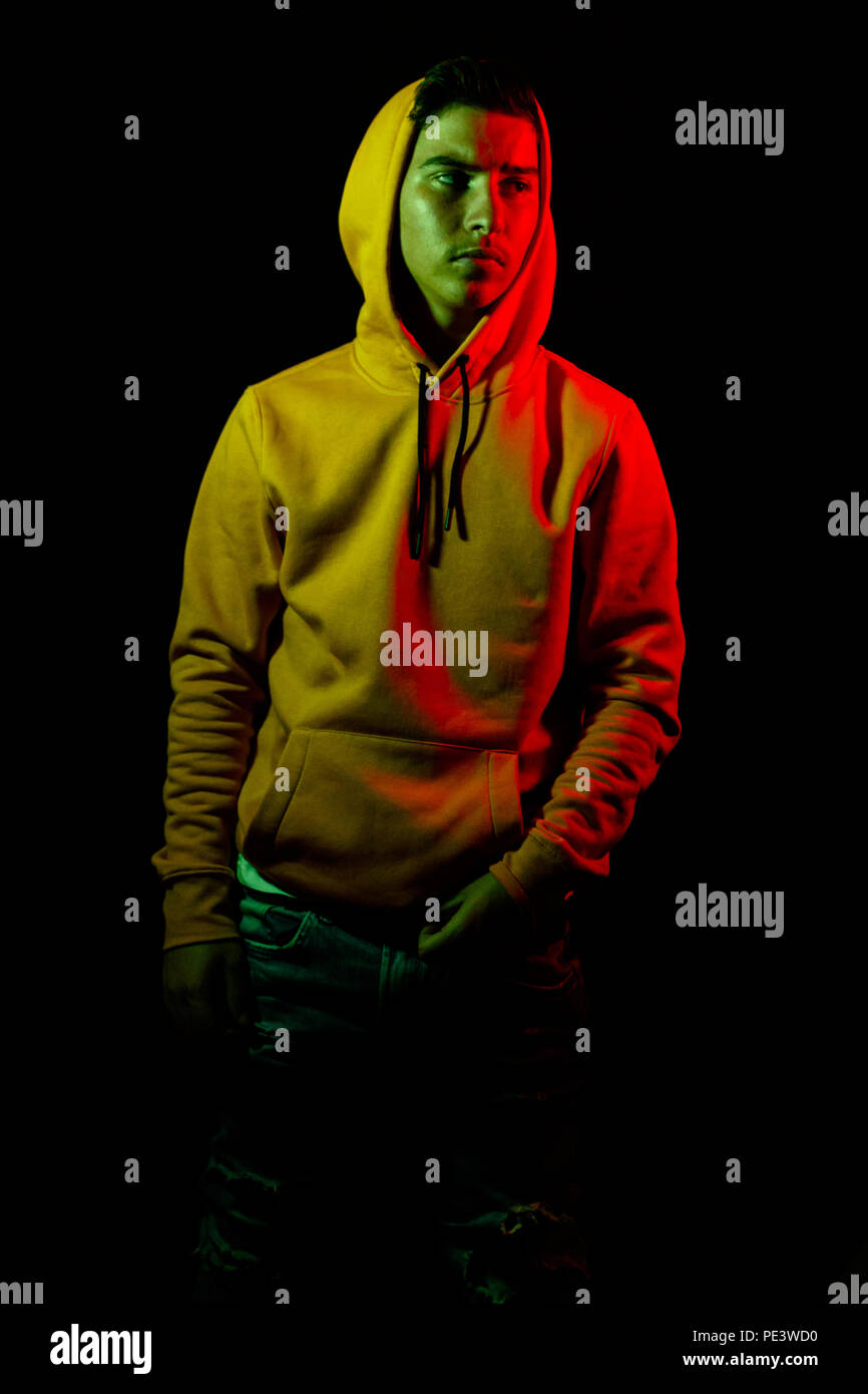 portrait of cool teen with yellow hoodie in green and red light Stock Photo