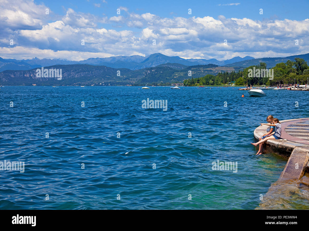 Two young girls sitting at lake promenade of Lazise, Garda lake, province Verona, Italy Stock Photo