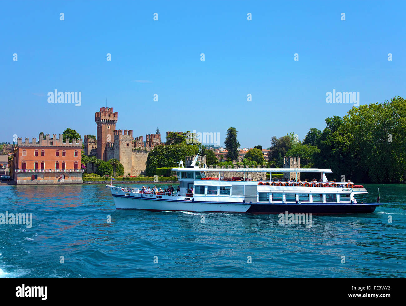 Ferry passing the Scaliger castle, 9 century at Villa Bernini park, Lazise, province Verona, Lake Garda, Italy Stock Photo