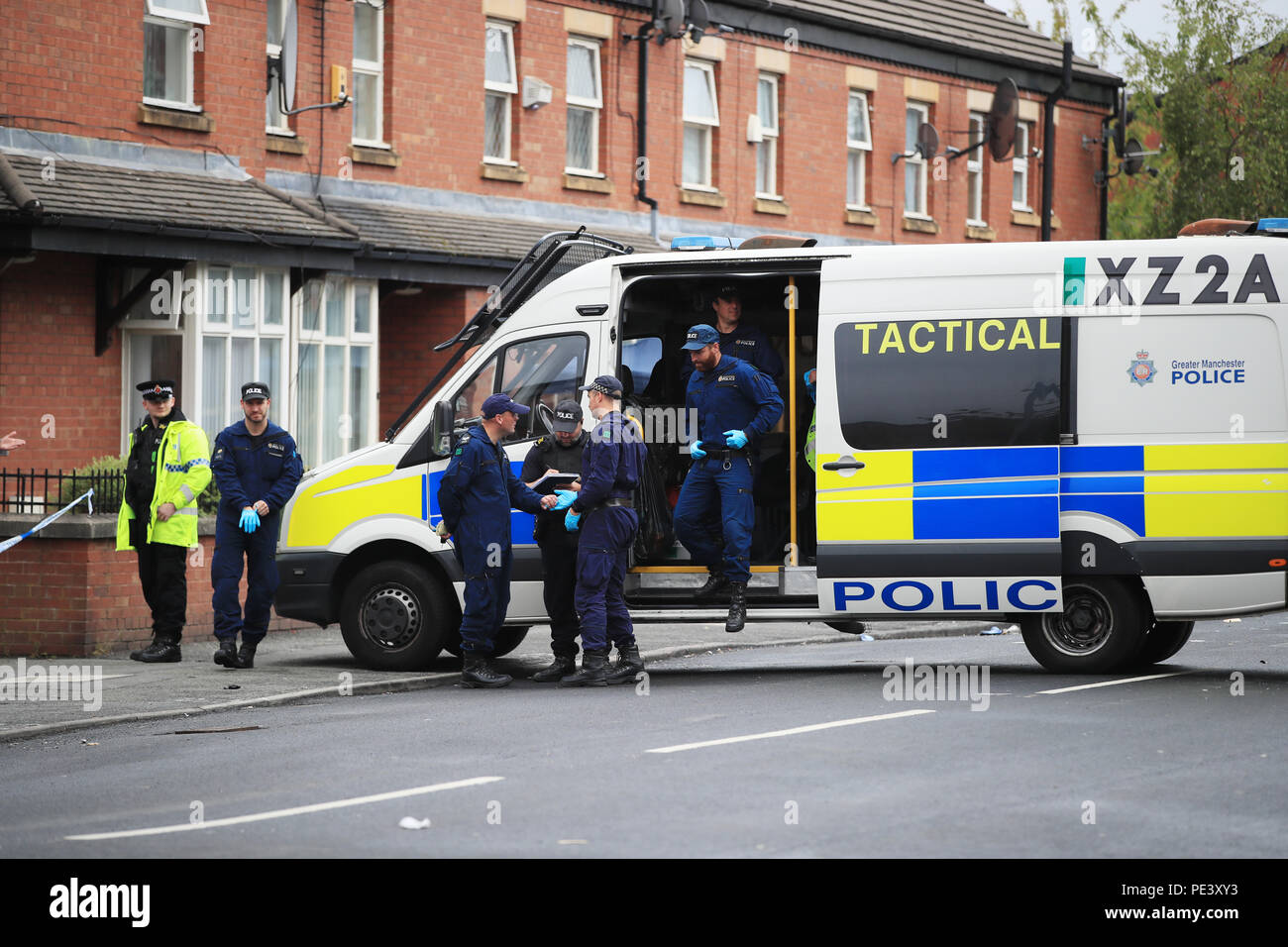Police from the Tactical Aid Unit arrive to carry out a fingertip search in Claremont Road, Moss Side, Manchester, where ten people, including two children were taken to hospital after reports of gunshots at a street party. Stock Photo
