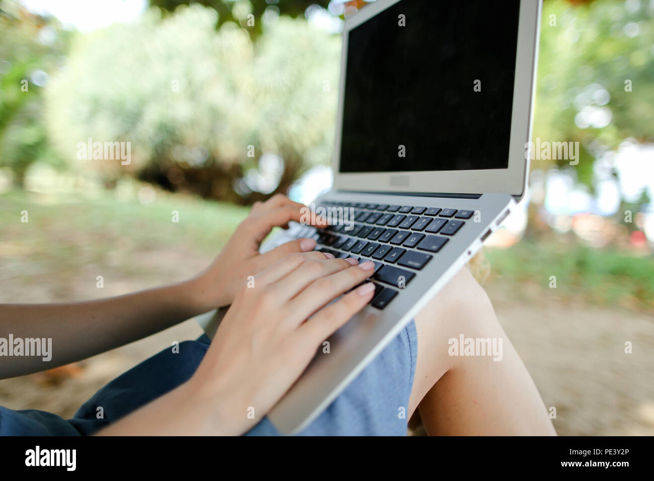Female nice hands using laptop with sand in background, black screen