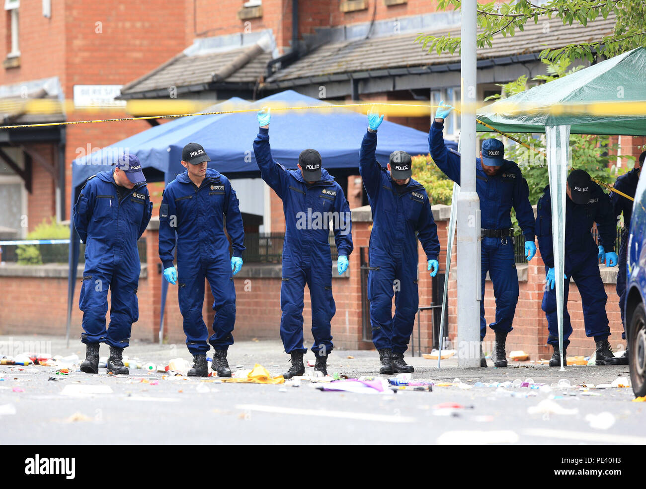 Police from the Tactical Aid Unit carry out a fingertip search in Claremont Road, Moss Side, Manchester, where ten people, including two children were taken to hospital after reports of gunshots at a street party. Stock Photo