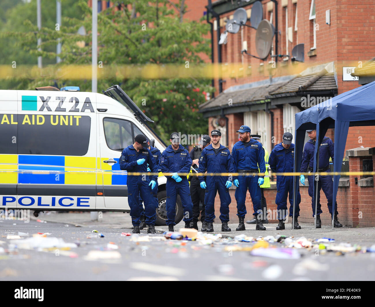 Police from the Tactical Aid Unit carry out a fingertip search in Claremont Road, Moss Side, Manchester, where ten people, including two children were taken to hospital after reports of gunshots at a street party. Stock Photo