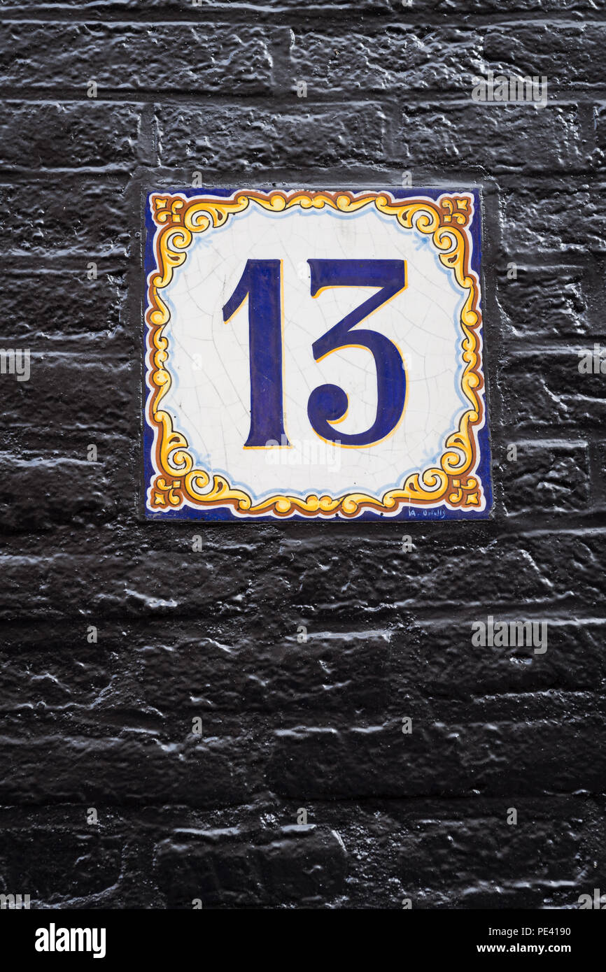 Number 13 on a ceramic tile fixed on a black painted brick wall in Amsterdam, Netherlands Stock Photo