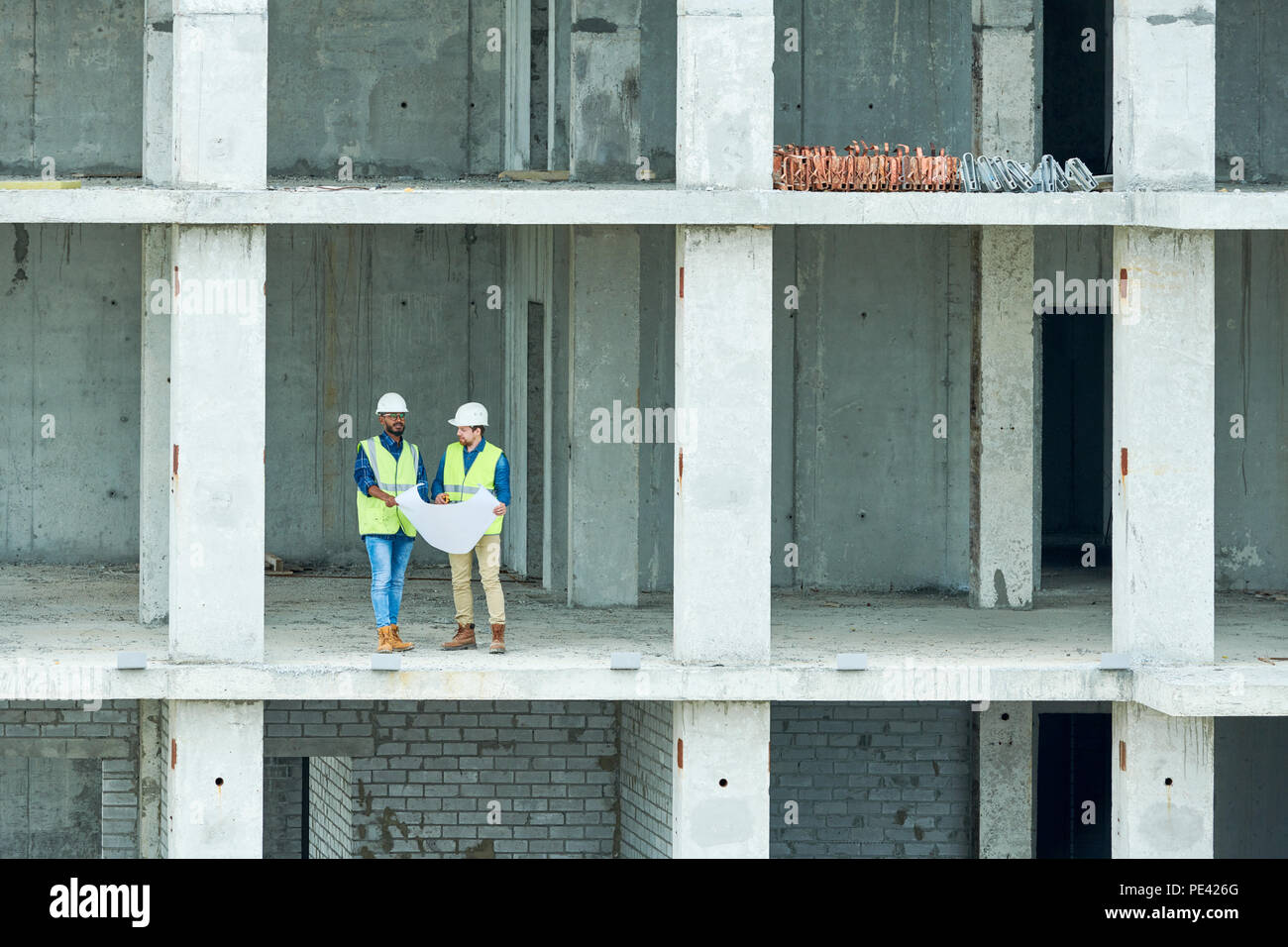 Construction engineers reading draft in unfinished building Stock Photo
