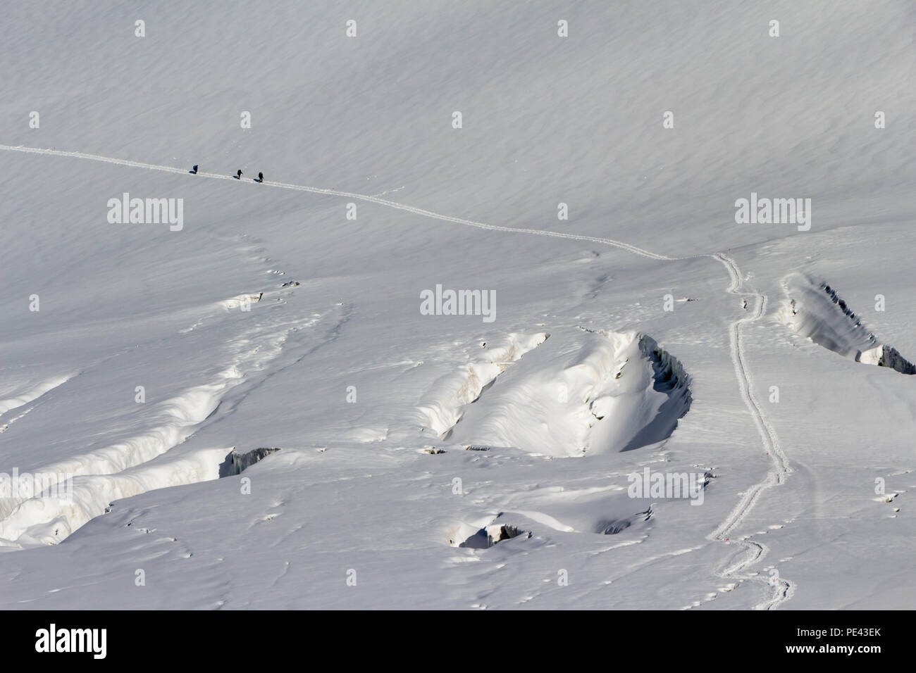 Mountaineers traverse a glacier near some crevasses Stock Photo