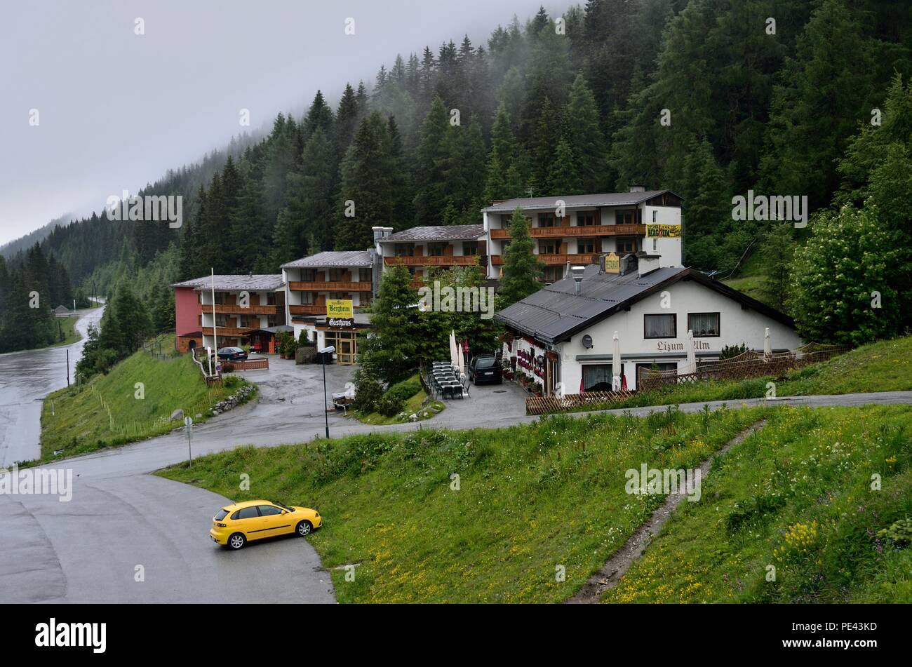 Alpin Hotel, Restaurant & Cafe, front grass corner, pine trees in the background, clouds wandering,View in a misty morning, Innsbruck, Austria, Europe Stock Photo