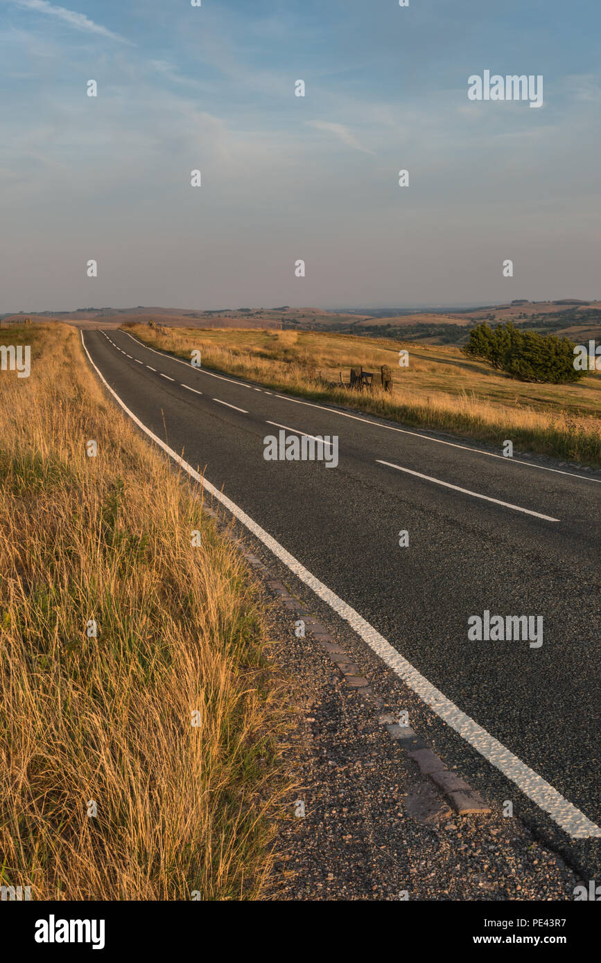 A deserted moorland road in the Staffordshire Peak District national park on a warm July evening with diagonal lines, England, UK Stock Photo