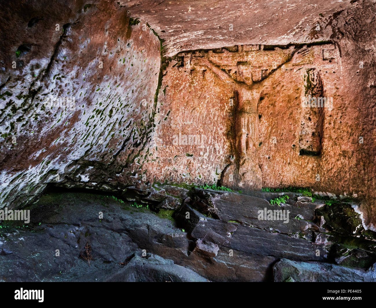 Crucifix carved into the wall of the Hermit's Cave under Cratcliffe Tor near Robin Hood's Stride in the Derbyshire Peak Disrtrict UK Stock Photo