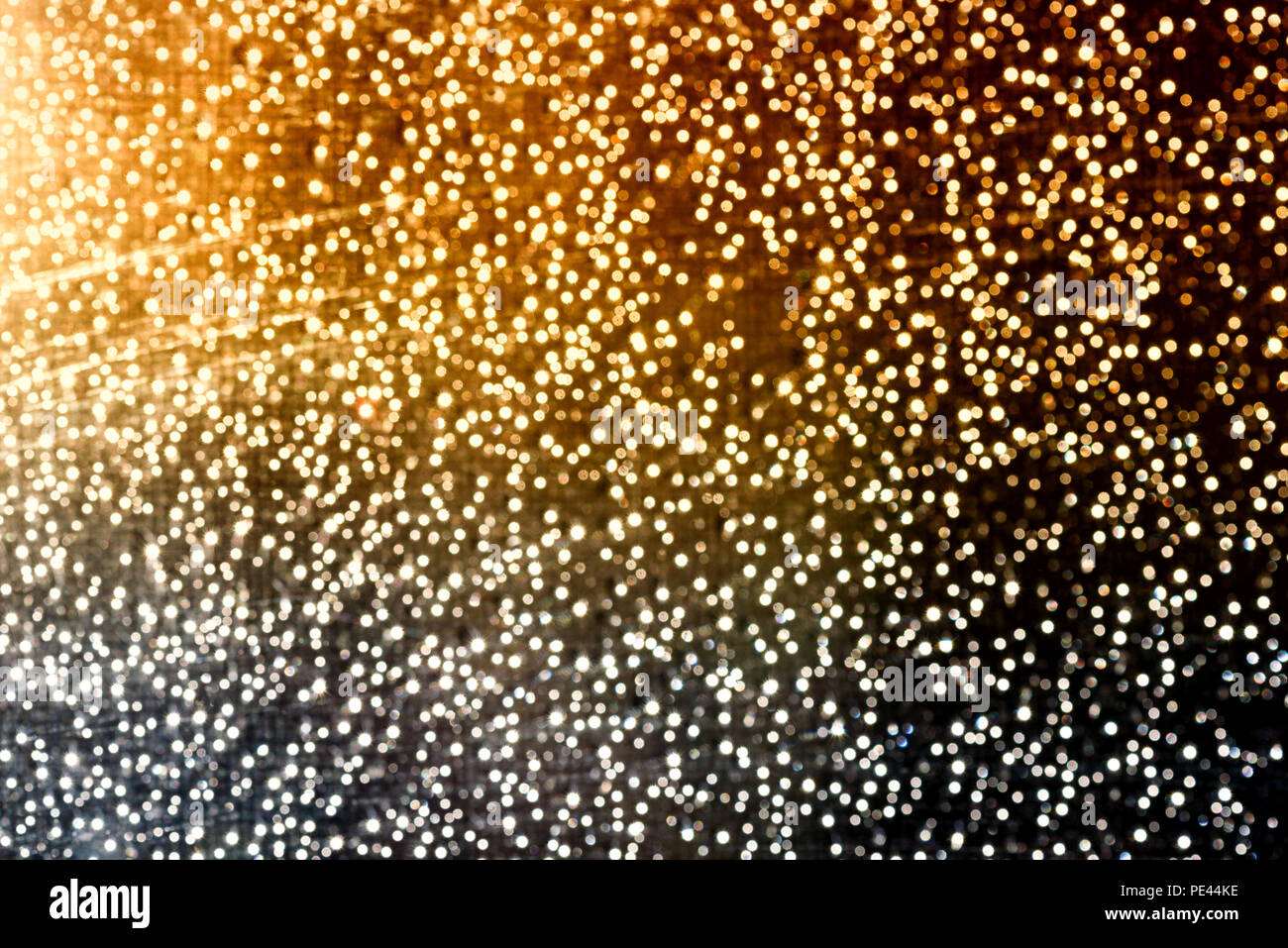 White flecks of defocused light creates a snowfall like bokeh effect in bright white colour with orange for festive christmas concepts and ideas Stock Photo