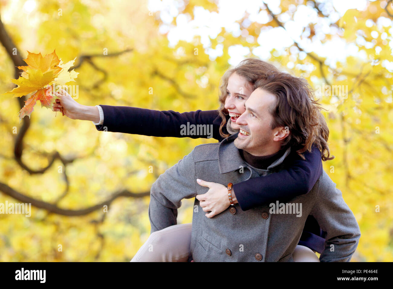 Happy young couple having fun in autumn forest piggyback ride, love ...