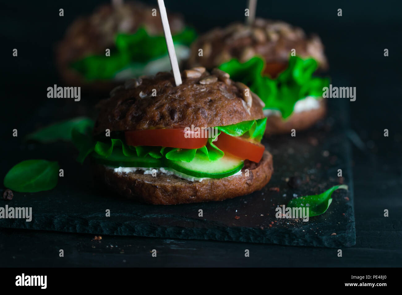 Green sandwich with salad, tomatoes, cucumbers and cream cheese on concrete desk. Stock Photo