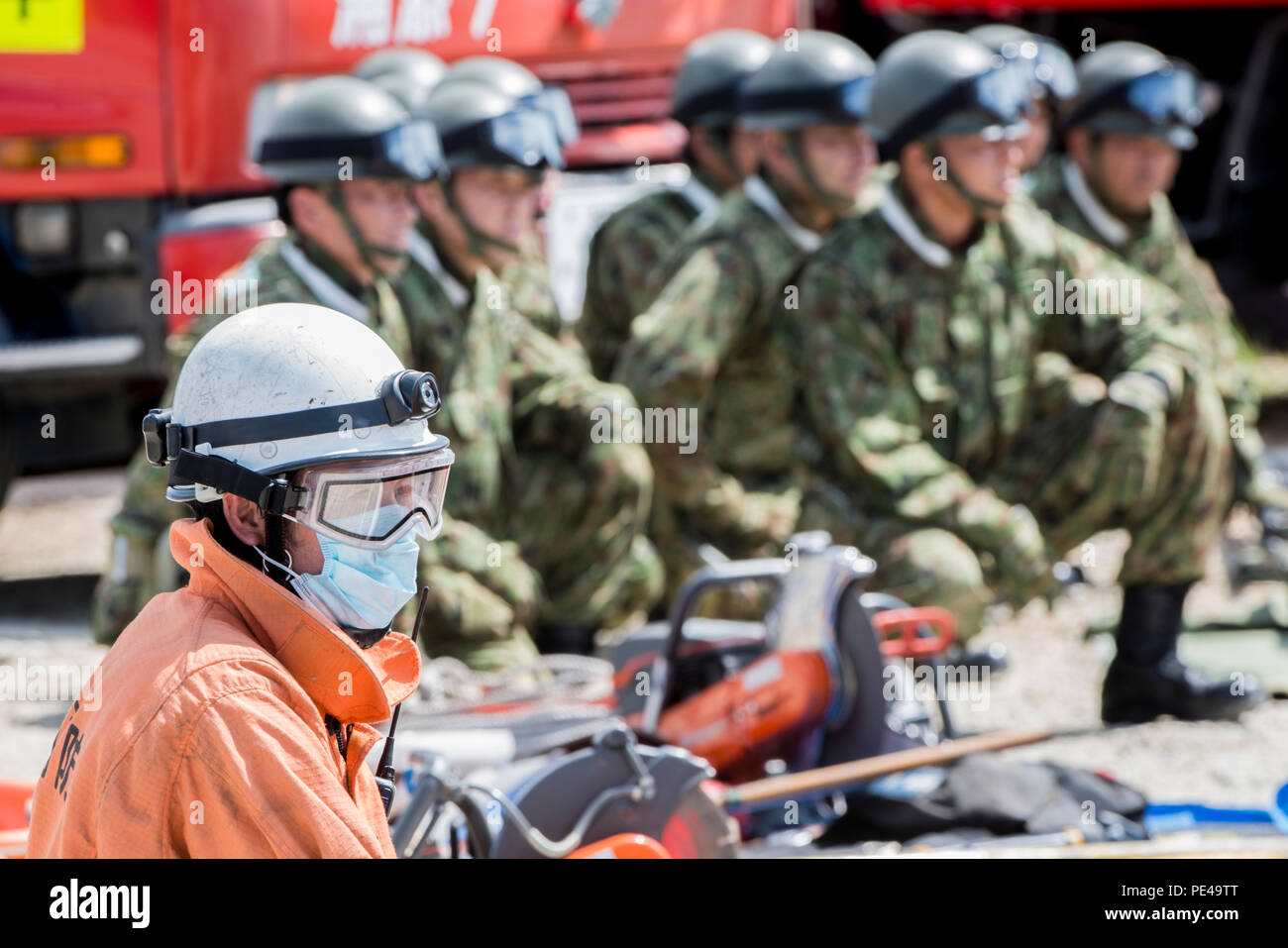 An Okinawa emergency responder waits alongside Japan Ground Self-Defense Force members before clearing rubble to search for simulated victims during an annual Okinawa Prefectural Government bilateral disaster response exercise at Atta Port, Japan, Sept. 5, 2015. The scenario centered on the evacuation and rescue of Okinawa inhabitants following a deadly tsunami hitting the island’s eastern coast. A total of 82 separate entities from the U.S. military, Japan Self-Defense Force and local emergency responders worked together to ensure the success of the exercise. (U.S. Air Force photo by Staff Sg - Stock Image