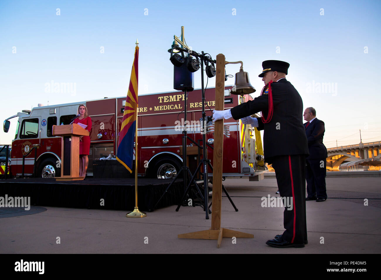 A firefighter with the Tempe Fire Department rings a ceremonious bell for the fallen firefighters of the Sept. 11, 2001, terrorist attacks, during a ceremony at the 9-11 Healing Field Memorial at Tempe Town Lake in Tempe, Ariz., Sept. 11, 2015. The traditional ringing of the bell signals when a firefighter is called to duty. Three rings represents the end of a firefighters duties.  In addition to the local firefighters, law enforcement, members of the greater Phoenix community, and Marines attended the ceremony. More than 800 Marines are currently in the valley of the sun as part of Marine Wee Stock Photo