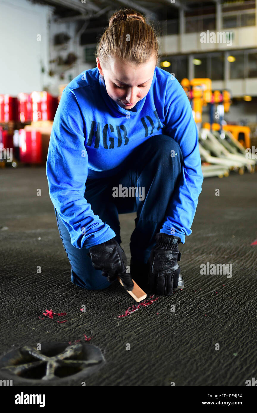 150916-N-QD363-103  ATLANTIC OCEAN (Sept. 16, 2015) – Airman Karissa Gutenberg scrapes tape off the deck in the hangar bay aboard the aircraft carrier USS Dwight D. Eisenhower (CVN 69). Dwight D. Eisenhower is underway conducting carrier qualifications. (U.S. Navy photo by Mass Communication Specialist 3rd Class Jameson E. Lynch/Released) Stock Photo