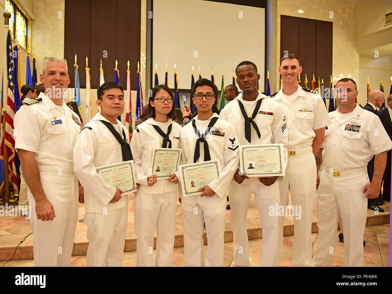 150917-N-TV402-335 YOKOSUKA, Japan (Sept. 17, 2015) -Commanding Officer, U.S. 7th Fleet flagship USS Blue Ridge (LCC 19), Capt. Kyle P. Higgins, left, Executive Officer, Cmdr. Nathan Fugate and Command Master Chief Mark Tomlinson, pose for a group photo with USS Blue Ridge Sailors, who participated in a naturalization ceremony at the Chapel of Hope. Forty men and women from 18 different countries recited the Oath of Allegiance to the United States and obtained U.S citizenship.  (U.S. Navy photo by Mass Communication Specialist Seaman Timothy D. Hale/ RELEASED) Stock Photo