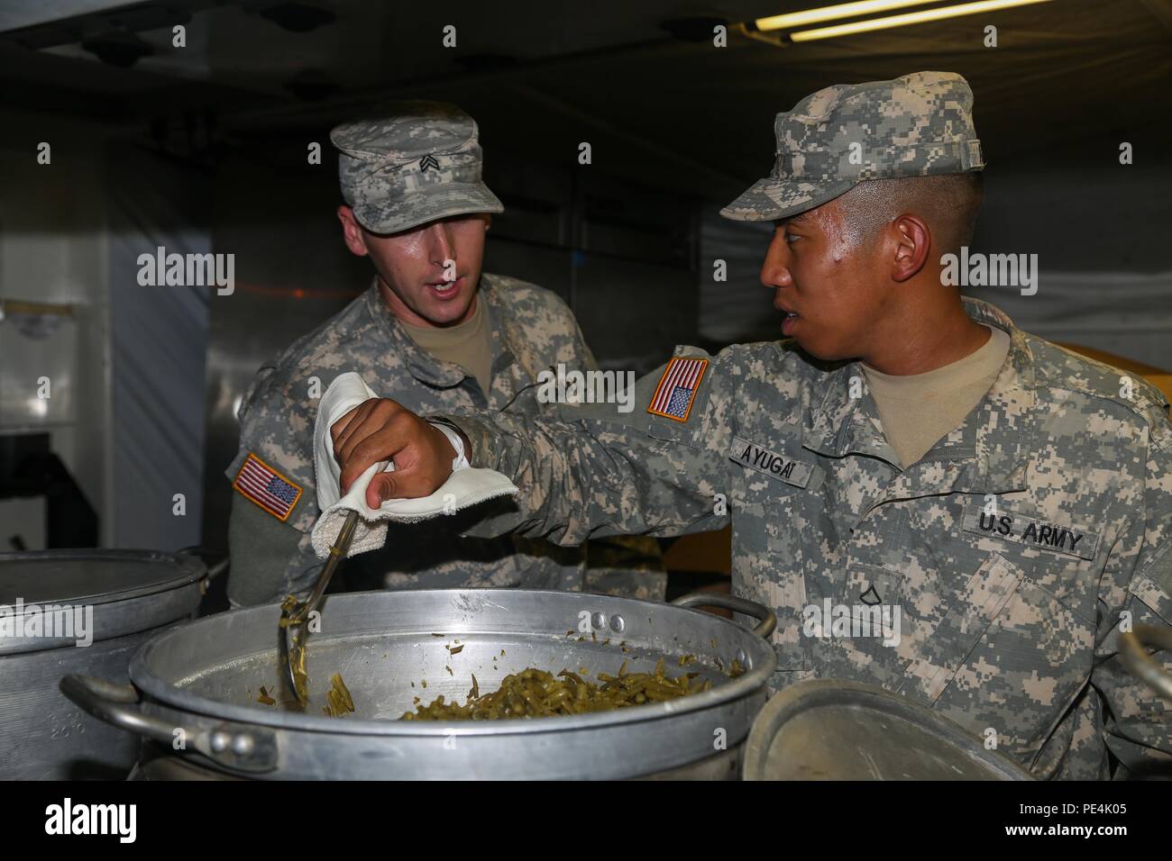 Sgt. Johnathan Valles, a food service specialist with Company F, 225th Brigade Support Battalion, 25th Infantry Division, coaches his Soldier, Pfc. Gerald Ayugat, on the proper way to prepare food Sept. 14 for over 500 Soldiers from 2 SBCT at East Range. A team of nine food specialists from Company F led by Staff Sgt. Derrick Lewellen prepare an evening meal for 2 SBCT Soldiers as well as train for their upcoming Field Conley Competition on Sept. 29. (U.S. Army photo by Sgt. Ian Ives, 2nd Stryker Brigade Combat Team Public Affairs/Released) Stock Photo