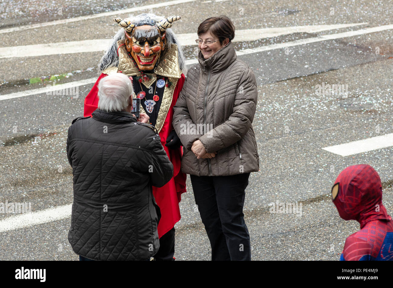 Man taking picture of Teufel's Narren, German devil's fool and woman, Spiderman looking, Strasbourg carnival parade, Alsace, France, Europe, Stock Photo