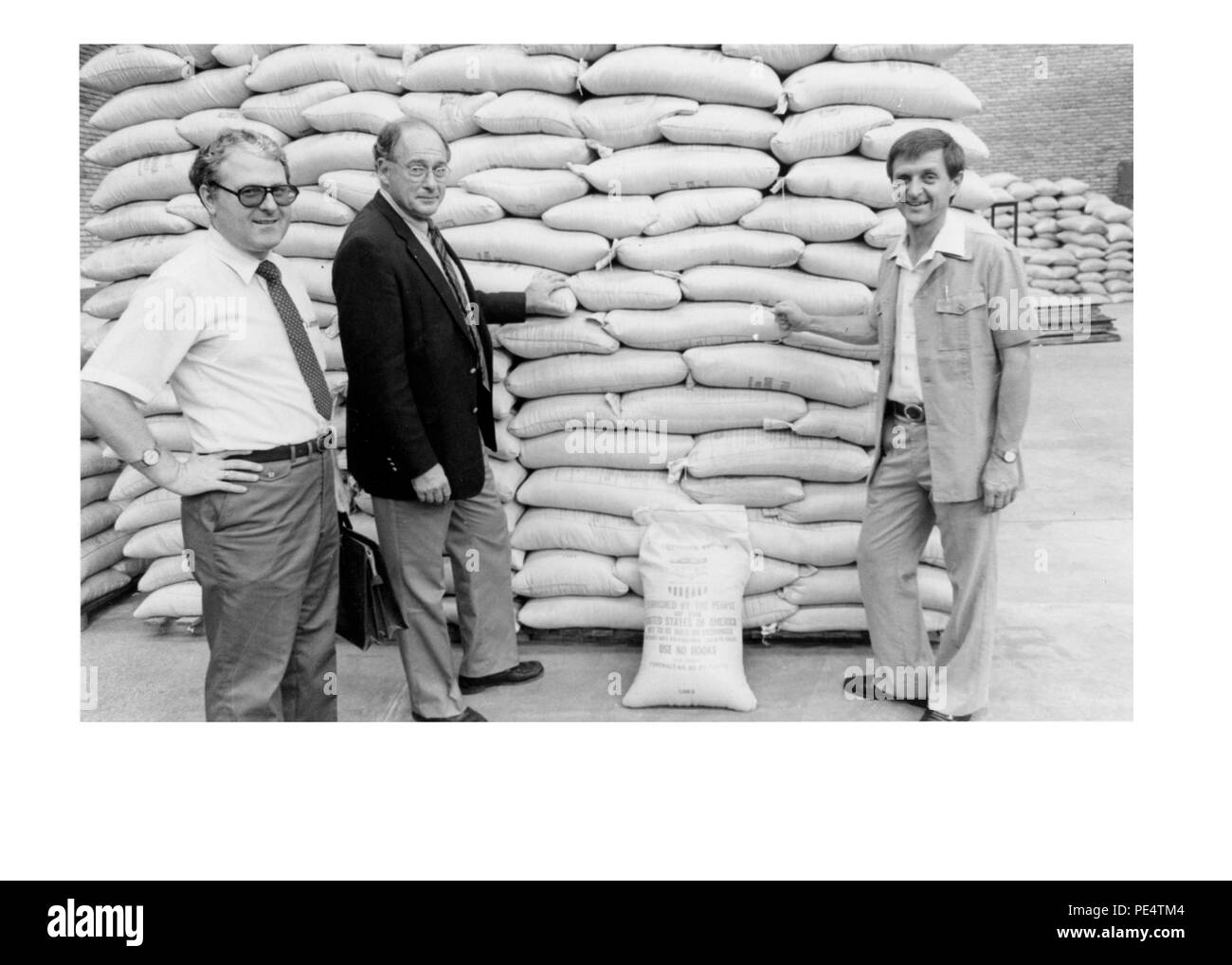 Food for Work in Rwanda - 1983 - American Ambassador John Blane and DCM Donald Hester examine USAID food stocked in ADRA warehouse in Kigali. Stock Photo
