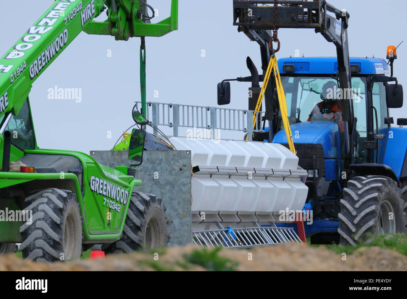 2 machines work together to position one section of a transmitter ready to be lifted onto the temporary mast at Emley Moor by helicopter crane. Stock Photo