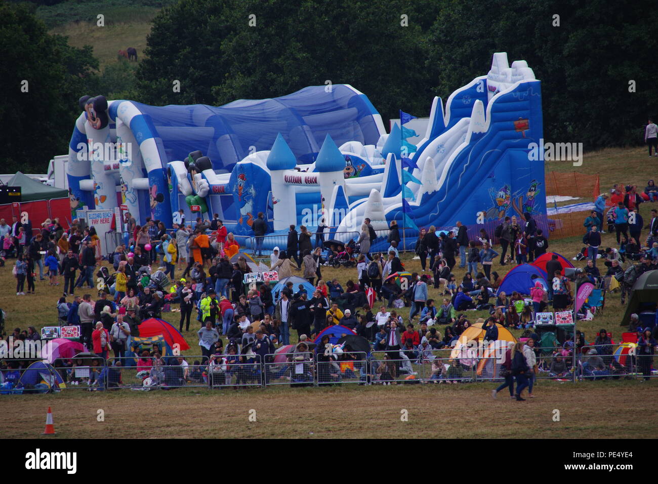 Large Bouncy Castles and Crowd in Wet Weather Clothing. Bristol Balloon Festival, Somerset, UK. August, 2018. Stock Photo